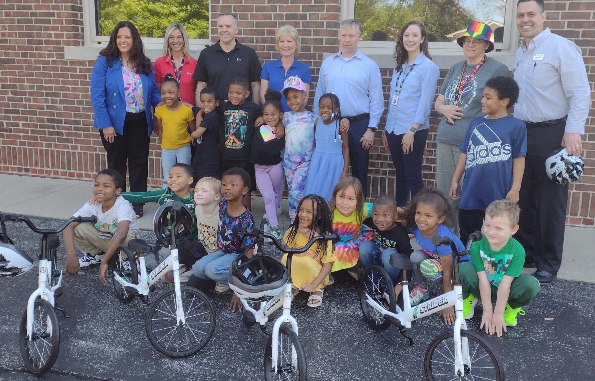 Mayor Misty Buscher (far left) along with principal Jim Hayes (far right) pose with some kindergarteners and their new training bikes.